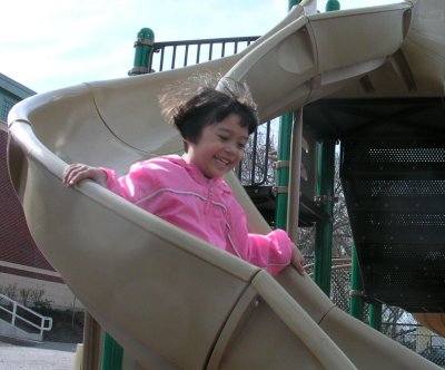 Mia going down a slide with jacket